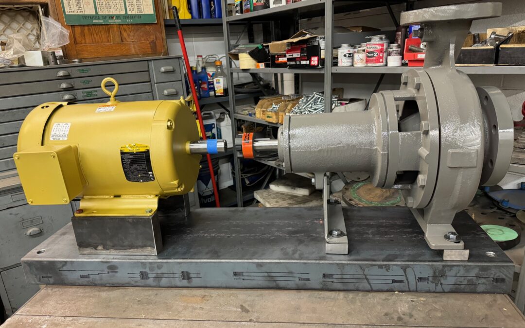 A Worthington D814 water pump with a yellow electric motor mounted on a metal table.